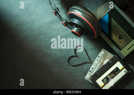 Lettore di cassette e cuffia sul pavimento di cemento. Forma di cuore della cassetta striscia di nastro. Vista superiore e copia spazio per il testo. Concetto di musica è il cuore. Foto Stock