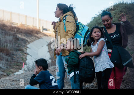 Una famiglia si guarda indietro a la recinzione di confine che divide gli Stati Uniti e il Messico vicino a Las Playas de Tijuana, dopo aver saltato la recinzione e di entrare negli Stati Uniti a San Ysidro, California, il 2 dicembre 2018. Foto di Ariana Drehsler/UPI Foto Stock