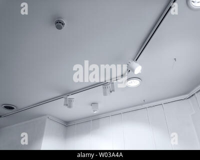 A fasci luminosi di forte intensità in exhibition hall. fila di lampade alogene in un ufficio interno Foto Stock
