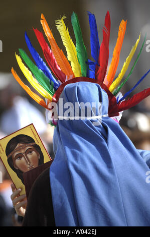 Una suora che indossa un Indiano headress conserva un dipinto raffigurante Kateri Tekakwitha in piazza san Pietro nella Città del Vaticano il 21 ottobre 2012. Papa Benedetto XVI ha nominato sette nuovi santi oggi, Kateri Tekakwitha della US, Jacques Berthieu della Francia, Maria Anna Cope di Germania, Pedro Calungsod dalle Filippine, Maria Schaffer di Germania, Giovanni Battista Piamarta d'Italia, Maria del Carmen di Spagna, in piazza San Pietro in Vaticano. UPI/Stefano Spaziani Foto Stock