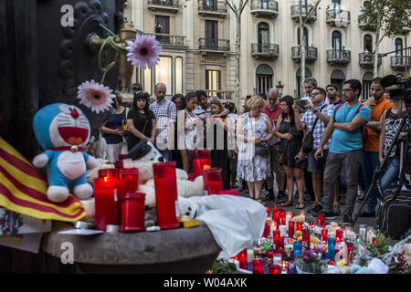 Le persone accanto a fiori, candele e altri elementi istituito presso il Font de Canaletes a Barcellona come hanno reso omaggio alle vittime dell'attentato di Barcellona, un giorno dopo un van arata nella folla, uccidendo 14 persone e il ferimento di oltre 100 il 18 agosto 2017. I piloti hanno arato il 17 agosto 2017. Foto di Angel Garcia/ UPI Foto Stock