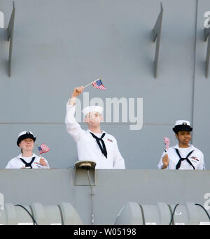 I marinai wave bandierine americane dal ponte della USS Ronald Reagan portaerei come esso ancorato alla Naval Air Station North Island in Coronado, California, il 6 luglio 2006. L'energia nucleare portaerei e il suo equipaggio di quasi 5.000 marinai tornato a San Diego dopo sei mesi di distribuzione per il Golfo Persico e Oceano Pacifico occidentale. È stata la prima missione per la nave essendo stato commissionato nel 2003. (UPI foto / Earl S.Cryer) Foto Stock