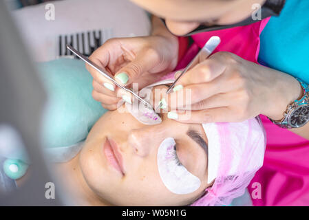 Donna master nel salone di bellezza sta lavorando su extension delle ciglia del cliente. Industria e professioni nel campo della bellezza Foto Stock