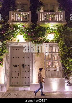 Un uomo cammina davanti a una storica e bella era coloniale edificio nel centro storico (Centro) di Cartagena, Colombia, con piante pendenti. Foto Stock