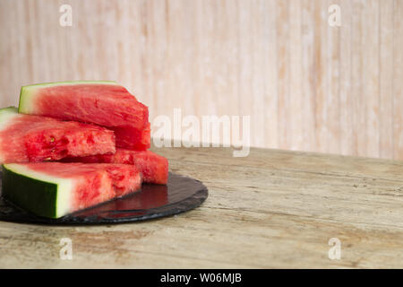 Triangolare di fette di cocomero sovrapposte su una piastra nera di ardesia bagnata nella messa a fuoco selettiva per spazio di copia Foto Stock