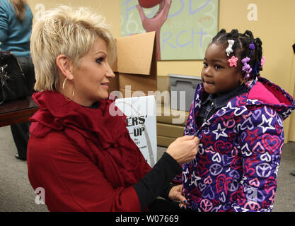 Brenda Warner, moglie dell'ex NFL quarterback Kurt Warner, aiuta De'Niya Moore (4) zip fino la sua nuova giacca durante un Warner riscaldamento invernale evento in San Luigi il 12 novembre 2012. Warner organizzazione per prima cosa, raccoglie circa 15.000 nuovi o usati con delicatezza cappotti e dà loro di quelli che sono nel bisogno. UPI/Bill Greenblatt Foto Stock