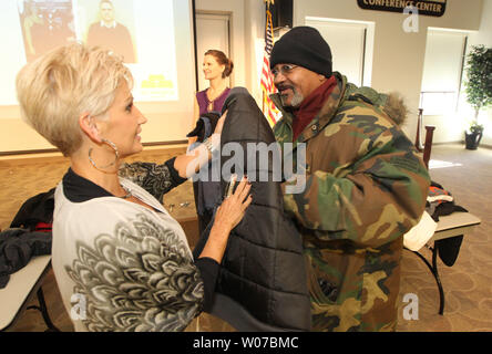 Brenda Warner, moglie dell'ex NFL quarterback Kurt Warner dà una mano a esercito veterano Steve Strozier durante il primo giorno di distribuzione della Warner's Warm-Up coat drive presso il San Patrizio Center di San Luigi il 12 novembre 2013. Si svolge ogni anno a partire dal 2001, il dolce-utilizzato cappotti sono date a coloro che sono nel bisogno, fornendo cappotti per oltre 150.000 data. UPI/Bill Greenblatt Foto Stock