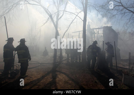 San Luigi dei vigili del fuoco di guardare nel fumo pesante come flussi di flessibile di estinguere i punti caldi su una casa dopo il fuoco completamente travolto i due piani di struttura in St. Louis, il 20 marzo 2014. UPI/Bill Greenblatt Foto Stock