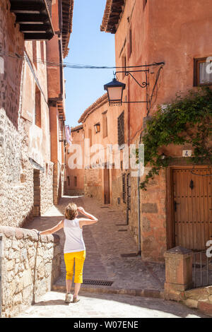 Donna che cammina lungo le strette strade di ciottoli nel medioevo spagnolo moresco della città murata di Albarracin in Montes Universales Aragona Spagna Foto Stock