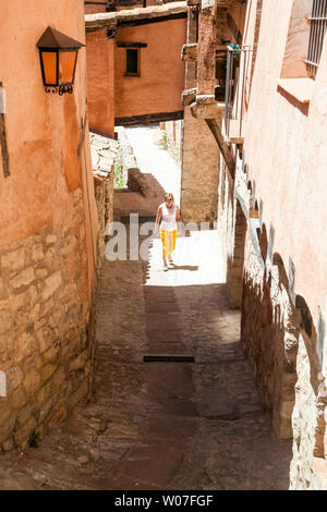 Donna che cammina lungo le strette strade di ciottoli nel medioevo spagnolo moresco della città murata di Albarracin in Montes Universales Aragona Spagna Foto Stock