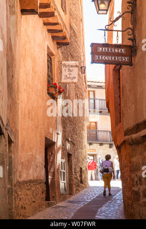 Donna che cammina lungo le strette strade di ciottoli nel medioevo spagnolo moresco della città murata di Albarracin in Montes Universales Aragona Spagna Foto Stock