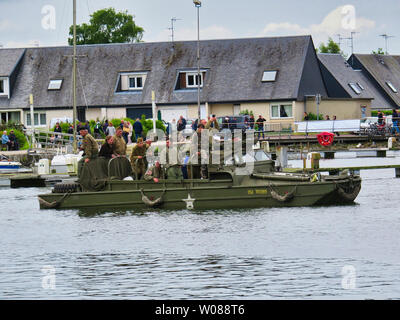 CARENTAN, Francia - 06 Giugno, 2019. Le forze speciali di uomini in camouflage uniformi in una landing craft durante un assalto anfibio dimostrazione. Diversionar Foto Stock