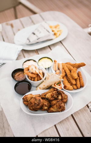 Diversi tipi di profonda snack fritti: pollo, formaggio, cipolla e tortillas su un tavolo di legno Foto Stock