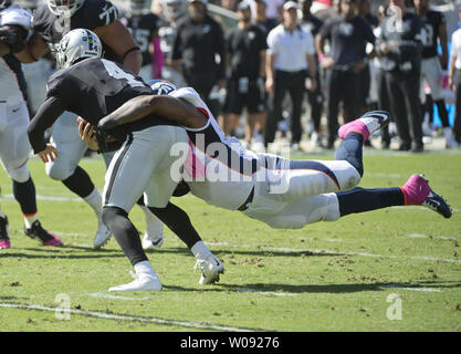 Oakland Raiders QB Derek Carr (4) è licenziato per un cantiere di cinque perdita da Denver Broncos Malik Jackson nel primo trimestre a O.co Coliseum di Oakland, la California il 11 ottobre 2015. I Broncos sconfitti i raider 16-10. Foto di Terry Schmitt/UPI Foto Stock