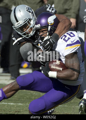 Minnesota Vikings RB Adrian Peterson (28) è portato verso il basso dalla Oakland Raiders Malcolm Smith nel primo trimestre a O.co Coliseum di Oakland, la California il 15 novembre 2015. Peterson ha funzionato per 203 yards come vichinghi sconfitti i raider 30-14. Foto di Terry Schmitt/UPI Foto Stock