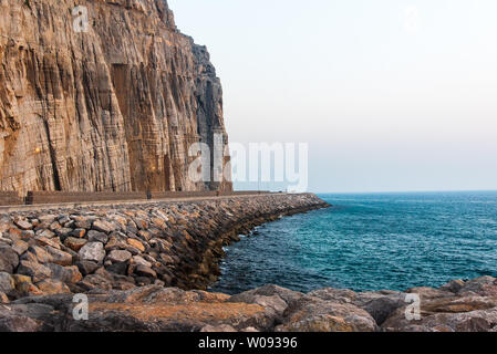 Panoramica strada costiera nel governatorato di Musandam di Oman circondata da rocce arenarie Foto Stock