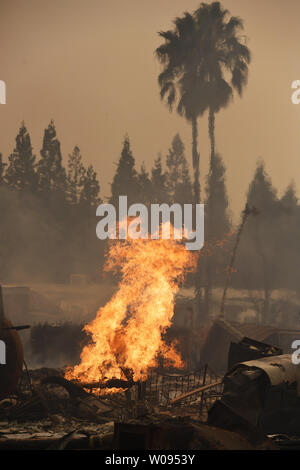 Vivere i getti di gas di scattare fino dalle rovine di viaggio fine del parco del rimorchio dopo incendi alimentati dal vento e bassa umidità distrutta in Santa Rosa, California il 9 ottobre 2017. Piena di fumo aria come migliaia di strutture bruciato. Foto di Terry Schmitt/UPI Foto Stock