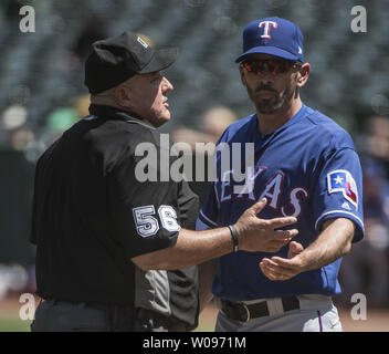 Texas Rangers manager Chris Woodward (R) sostiene con piastra home arbitro Eric Cooper (56) dopo una chiamata rovesciato nella terza inning contro Oakland atletica presso il Colosseo a Oakland, la California il 24 aprile 2019. Foto di Terry Schmitt/UPI Foto Stock