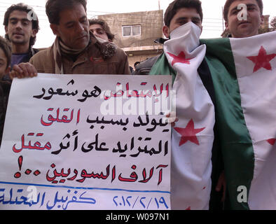 Dimostranti siriani tenere cartelli e Siriana e bandiere di indipendenza durante una manifestazione di protesta contro la Siria il Presidente Bashar al-Assad in Kafranbel, Siria, 19 febbraio 2012. Opposizione siriana chiamato per la disobbedienza civile nella capitale Damasco, mentre l'Egitto ha ricordato il suo ambasciatore a Damasco, alla televisione di stato detto domenica, in ciò che sembrava essere la fase più recente di una serie di diplomatico arabo si muove per intensificare la pressione sul Presidente Bashar al-Assad, che sta cercando di schiacciare una rivolta popolare in Siria. UPI Foto Stock