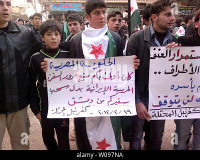 Dimostranti siriani tenere indicazioni durante una manifestazione di protesta contro la Siria il Presidente Bashar al-Assad in Kafranbel, Siria, 19 febbraio 2012. Opposizione siriana chiamato per la disobbedienza civile nella capitale Damasco, mentre l'Egitto ha ricordato il suo ambasciatore a Damasco, alla televisione di stato detto domenica, in ciò che sembrava essere la fase più recente di una serie di diplomatico arabo si muove per intensificare la pressione sul Presidente Bashar al-Assad, che sta cercando di schiacciare una rivolta popolare in Siria. UPI Foto Stock