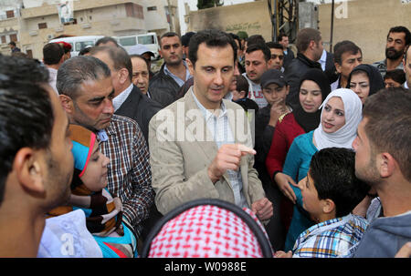 In questa foto rilasciata dalla Siria il national news agency, il Presidente siriano Bashar al-Assad colloqui con persone durante la sua visita a Ein al-Tinah village, a nord-est di Damasco, in Siria il 20 aprile 2014. Il leader siriano ha visitato anche la vicina cristiana antica città di Maaloula la Domenica di Pasqua come egli cerca di convincere le minoranze che il governo è il loro migliore protezione contro islamisti inflessibile. UPI Foto Stock