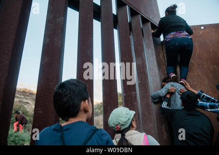 I migranti scavalcare la recinzione di confine che divide gli Stati Uniti e il Messico il 2 dicembre 2018 vicino a Las Playas de Tijuana, Messico. Foto di Ariana Drehsler/UPI Foto Stock