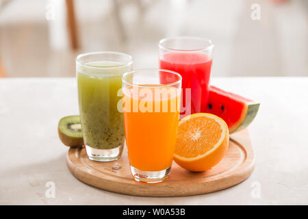 Succhi di frutta freschi frappè tre vetro verde rosso arancio frutti tropicali acqua di melone e kiwi, arancione. Messa a fuoco selettiva Foto Stock