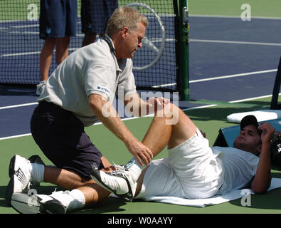 Un trainer lavora su Andy Roddick di crampi alle gambe durante il Masters di tennis Canada finale al centro Rexall Agosto 1, 2004 a Toronto in Canada. Roddick ha infine perso la partita 5-7, 3-6 per il numero uno al mondo Roger Federer. (UPI foto/Christine masticare) Foto Stock