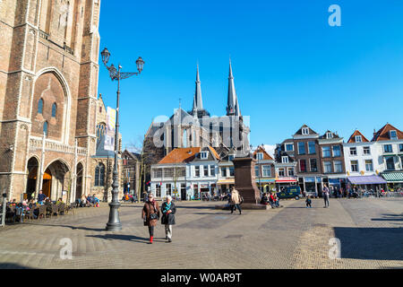 Delft, Paesi Bassi - 8 Aprile 2016: Colorful street view con case olandesi tradizionali sulla piazza, la chiesa, il popolo a piedi nel centro cittadino di popolari Ho Foto Stock