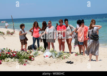 I turisti pagano i loro aspetti di fronte un ripiego memorial presso la spiaggia vicino al Imperial Marhaba resort che è stato attaccato da un bandito in Sousse, Tunisia, 29 giugno 2015.Lo Stato islamico (ISIS) gruppo rivendicato la responsabilità per il massacro perpetrato il 27 giugno in un mortale beach resort attentato che ha ucciso quasi 40 persone, la maggior parte di essi turisti britannici. Foto di Khaled Nasraoui/UPI Foto Stock