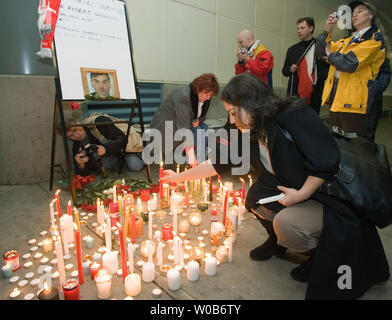 Una donna mette una candela accesa al memoriale e veglia a lume di candela per Robert Dziekanski frequentato da diverse centinaia di persone, molti dalla locale Comunità polacca presso gli Arrivi Internazionali, YVR Vancouver Airport, Richmond, British Columbia, 17 novembre 2007. Immigrato polacco Dziekanski è morto dopo essere stato tasered diverse volte e lottò per il pavimento dal RCMP ufficiali come hanno tentato di arrestare lui presso gli Arrivi Internazionali di YVR Vancouver Airport il 14 ottobre 2007. (UPI foto/Heinz Ruckemann) Foto Stock