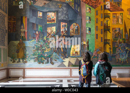 Donne in viaggio, vista posteriore di due donne con zaini guardando la colorata per Krohg affresco all'interno della Galleria Est del Municipio di Oslo, Norvegia. Foto Stock