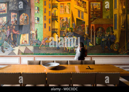 Municipio di Oslo, vista di una giovane donna a camminare lungo la colorata per Krohg affresco all'interno della Galleria Est del Municipio di Oslo (Radhus), Norvegia. Foto Stock
