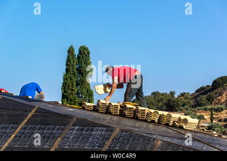 Gli uomini di installare le tegole. Foto Stock