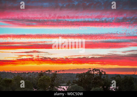 Bande di nuvole colorate attraverso il cielo al tramonto guardando verso il Portogallo dalla Costa Esuri, Ayamonte, Spagna oltre il Fiume Guadiana Foto Stock