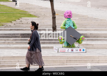 Glasgow, Scotland, Regno Unito - 22 Giugno 2019: due giovani donne a camminare lungo la moderna statua del "nostro Wullie' anteriore della nuova città di Glasgow College Foto Stock
