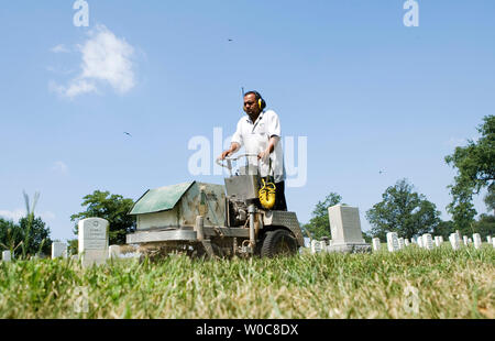 Un uomo aziona un trattore che stabilisce la calce tra lapidi al Cimitero Nazionale di Arlington, il 21 luglio 2008 in Arlington, Virginia. Il Professional Landcare Network (pianeta) ha tenuto la sua dodicesima Giornata annuale del servizio con centinaia di paesaggio, prato, attenzione e cura della struttura specialisti provenienti da tutta la nazione di trascorrere una giornata la pacciamatura, alberi cavi con protezione di alleggerimento, la potatura, la calcinazione, semina e aerare presso il Cimitero Nazionale di Arlington. (UPI foto/Patrick D. McDermott) Foto Stock