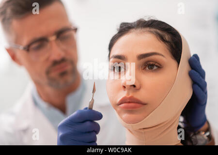 Imprenditrice indossando un bendaggio sulla faccia prima di un intervento di chirurgia plastica Foto Stock