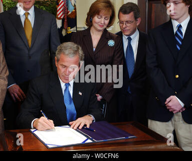 Il Presidente George W Bush firma il Garrett Lee Smith Memorial agiscono in legge il 21 ottobre 2004 presso la Casa Bianca a Washington. L'Atto introduce il supporto per mentale e salute comportamentale su American college campus. Membri della famiglia di Garrett Smith e i membri del Congresso degli Stati Uniti a guardare. (UPI foto/Michael Kleinfeld) Foto Stock