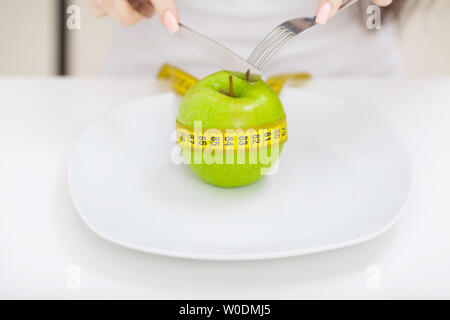 La dieta. Close up foto di misura di nastro avvolto attorno un Apple sulla piastra bianca Foto Stock