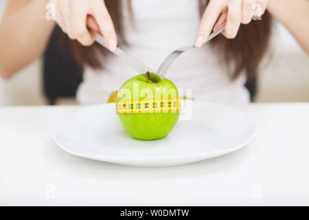 La dieta. Close up foto di misura di nastro avvolto attorno un Apple sulla piastra bianca Foto Stock