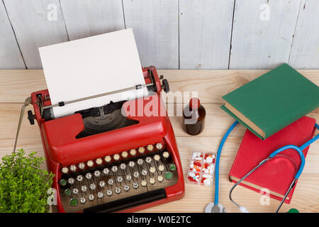 Medicina di prescrizione o di diagnosi medica - medico workplace con stetoscopio blu, pillole, rosso nastri inchiostratori per macchine da scrivere con carta bianca sul tavolo di legno Foto Stock