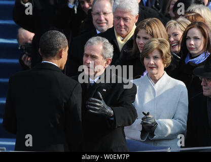 Il presidente Barack Obama (L) è abbracciato dall ex Presidente George W Bush dopo che Obama ha prestato giuramento come la quarantaquattresima Presidente degli Stati Uniti a West passi del Campidoglio, il 20 gennaio 2009. Sono anche mostrati l'ex Presidente Bill Clinton (top), il Sen. Hillary Clinton e Laura Bush. (UPI foto/Pat Benic) Foto Stock