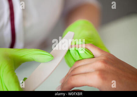 Manicure. Abile maestro di manicure file tiene nelle sue mani mentre si lavora nel suo salone di bellezza Foto Stock