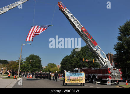 I membri dell'Arlington County Fire Department e New York City Fire Department marzo sotto una bandiera americana durante una cerimonia in cui i membri dei Vigili del Fuoco di New York ha dato un pezzo di acciaio dal World Trade Center di Arlington County Fire Department per loro grazie al servizio su 9/11, in Arlington, in Virginia, il 29 agosto 2010. UPI/Kevin Dietsch Foto Stock