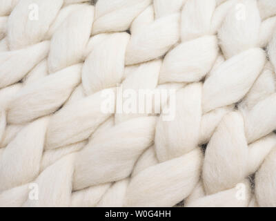 Lana Merinos maglia fatti a mano coperta di grandi dimensioni, super chunky filato, concetto alla moda. Close-up del tessuto lavorato a maglia a una coperta di lana merinos sfondo Foto Stock