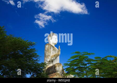 Bianco grande statua del Buddha il sollevamento ad alto contrasto con il blu del cielo senza nuvole al Wat Ek Phnom, nei pressi di Battambang, Cambogia Foto Stock