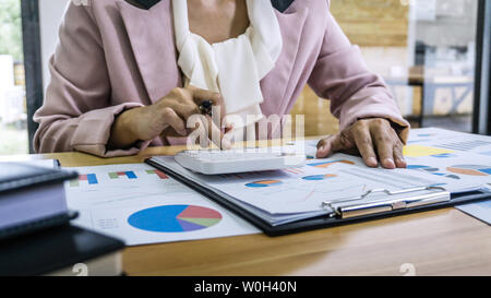 Business donna contabile che lavora e calcolando i dati finanziari sul grafico documenti, facendo finanziare in workstation. Foto Stock