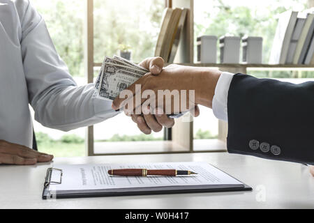 Imprenditore denaro di handshake di fatture del dollaro nelle mani da mentre dare successo la trattativa, la corruzione attiva e passiva del concetto. Foto Stock
