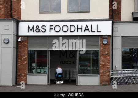 Ashtead, Surrey, Regno Unito - Marks & Spencer M&S Foodhall negozio di fronte esterno sulla strada alta con il cliente disabile di entrare su una mobilità scooter Foto Stock